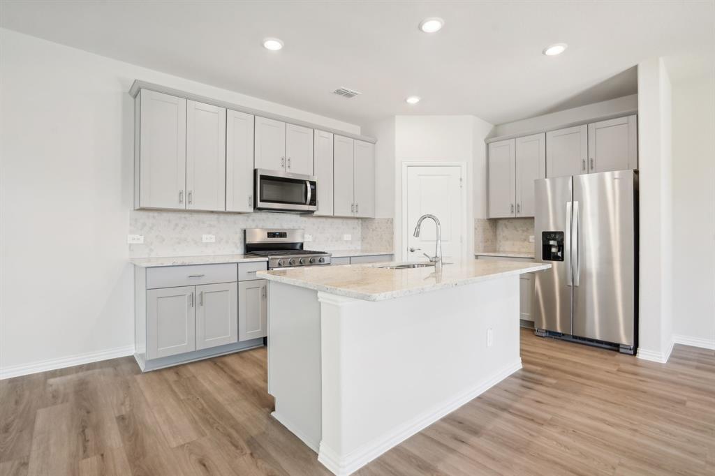 a kitchen with cabinets stainless steel appliances and wooden floor