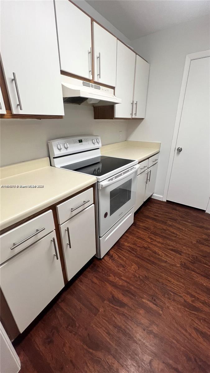 a kitchen with stainless steel appliances a white stove top oven cabinets and a wooden floor