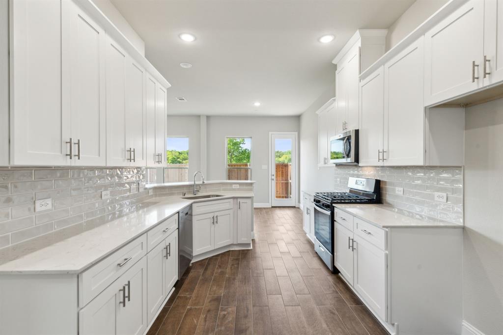 a kitchen with granite countertop a sink stove cabinets and wooden floor