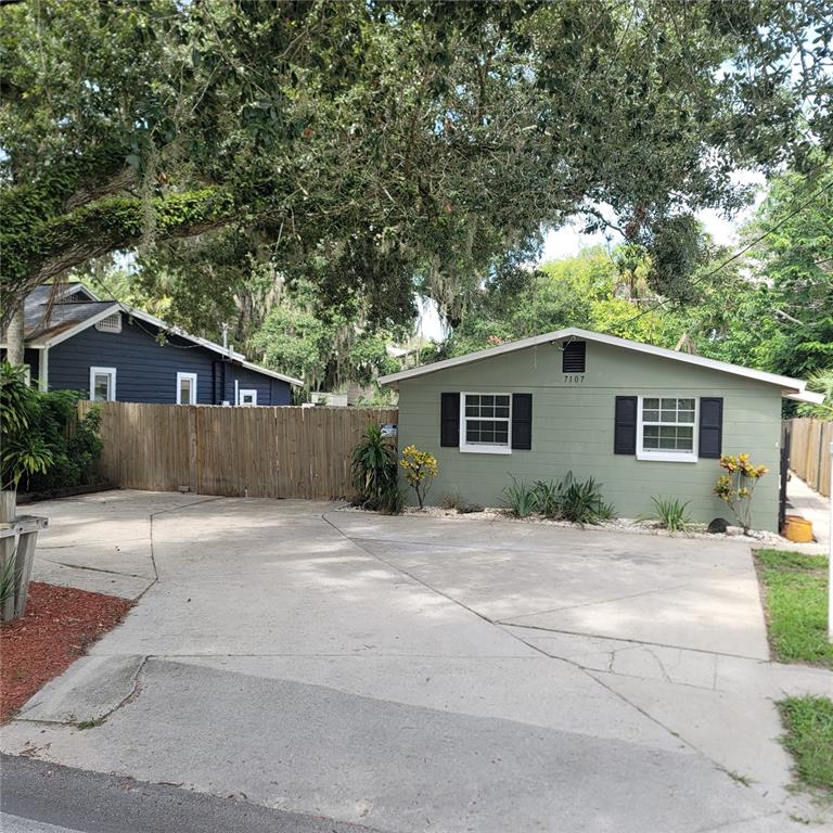 a view of a house with a yard and large tree