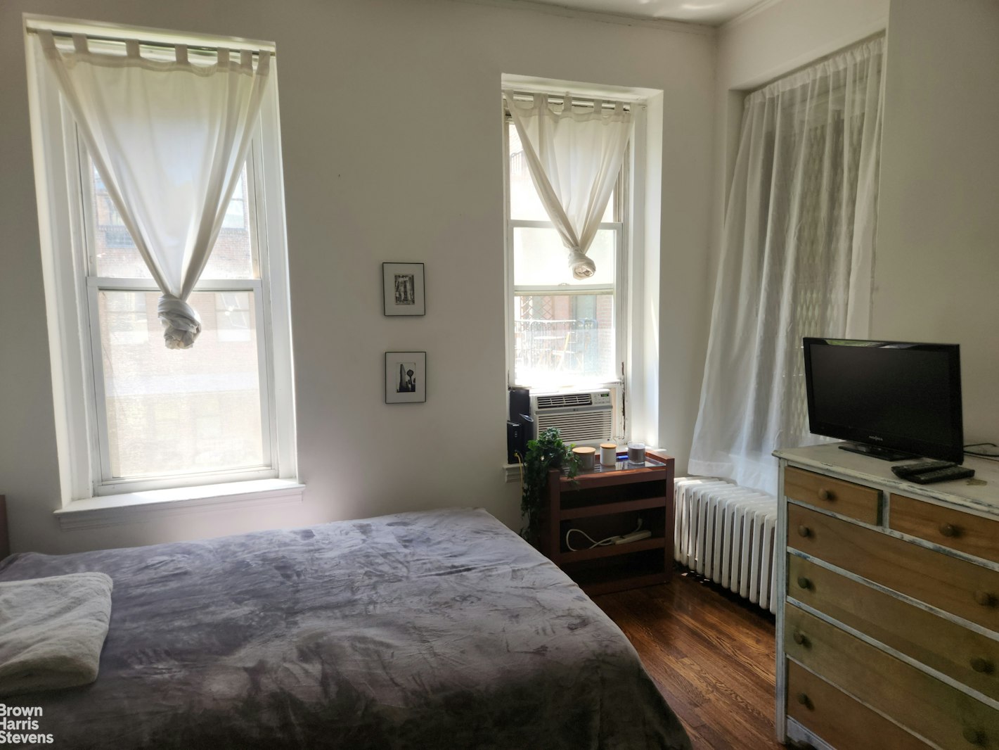 a bedroom with a bed and a flat tv screen on dresser