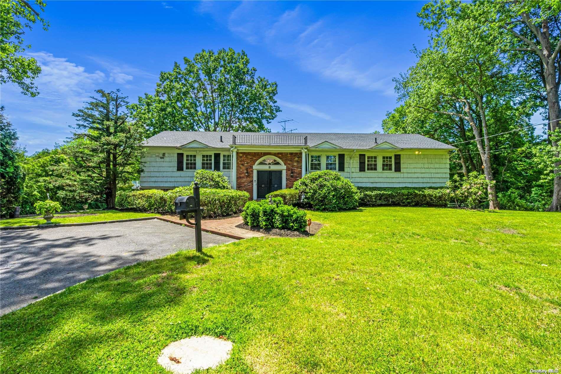 a view of house in front of a big yard with large trees