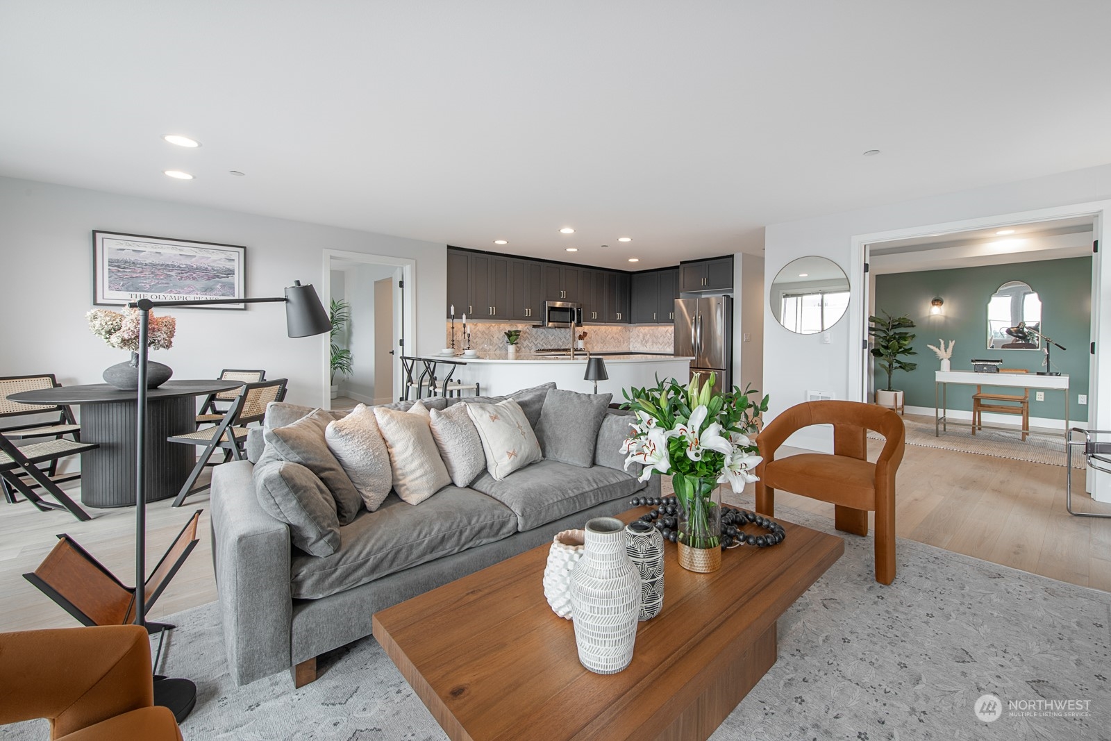 a living room with furniture potted plant and kitchen view