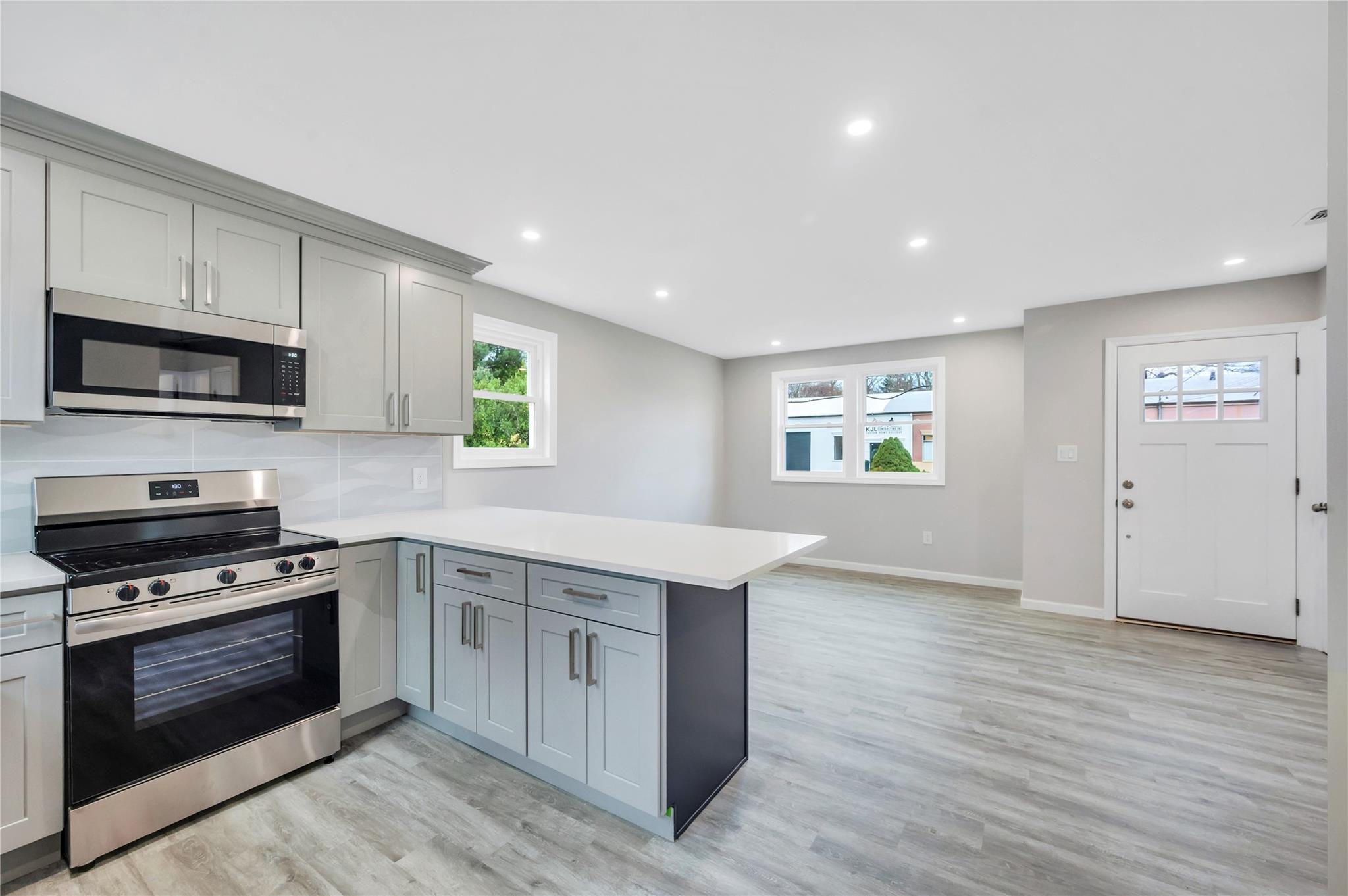 Kitchen with kitchen peninsula, gray cabinets, a healthy amount of sunlight, and appliances with stainless steel finishes