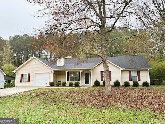 a view of a white house next to a yard with a large tree