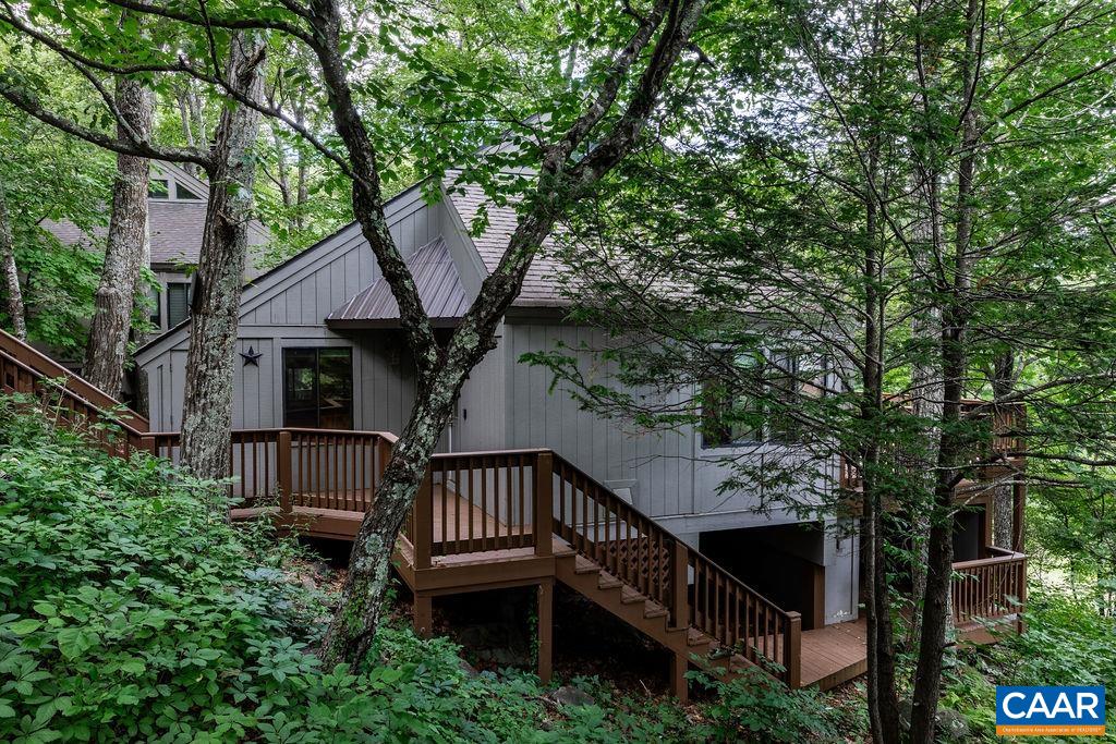 a view of a house with large trees and wooden fence