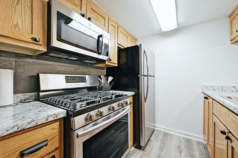 a kitchen with granite countertop cabinets stainless steel appliances and wooden floor