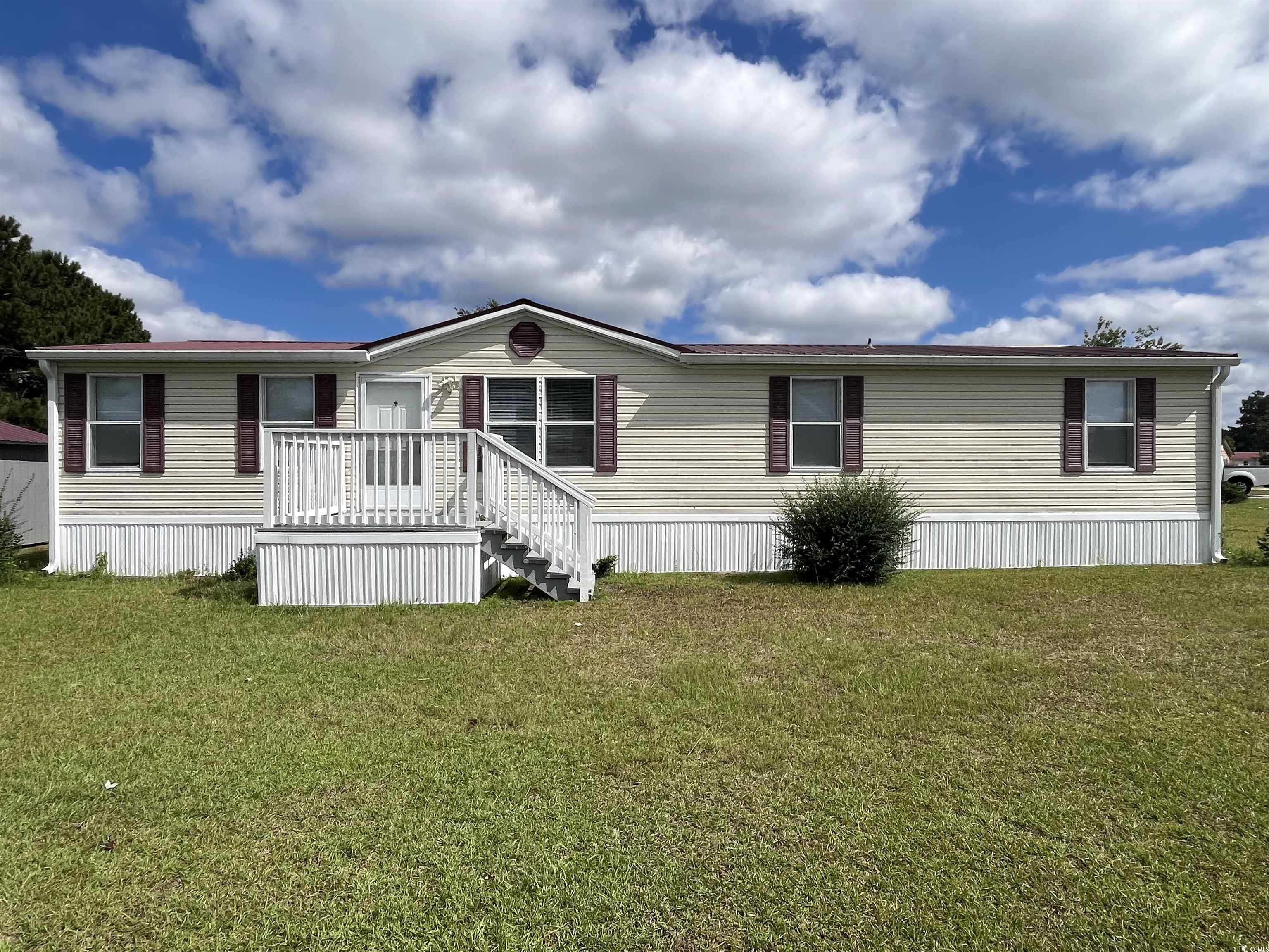 Back of property featuring a lawn and a wooden dec