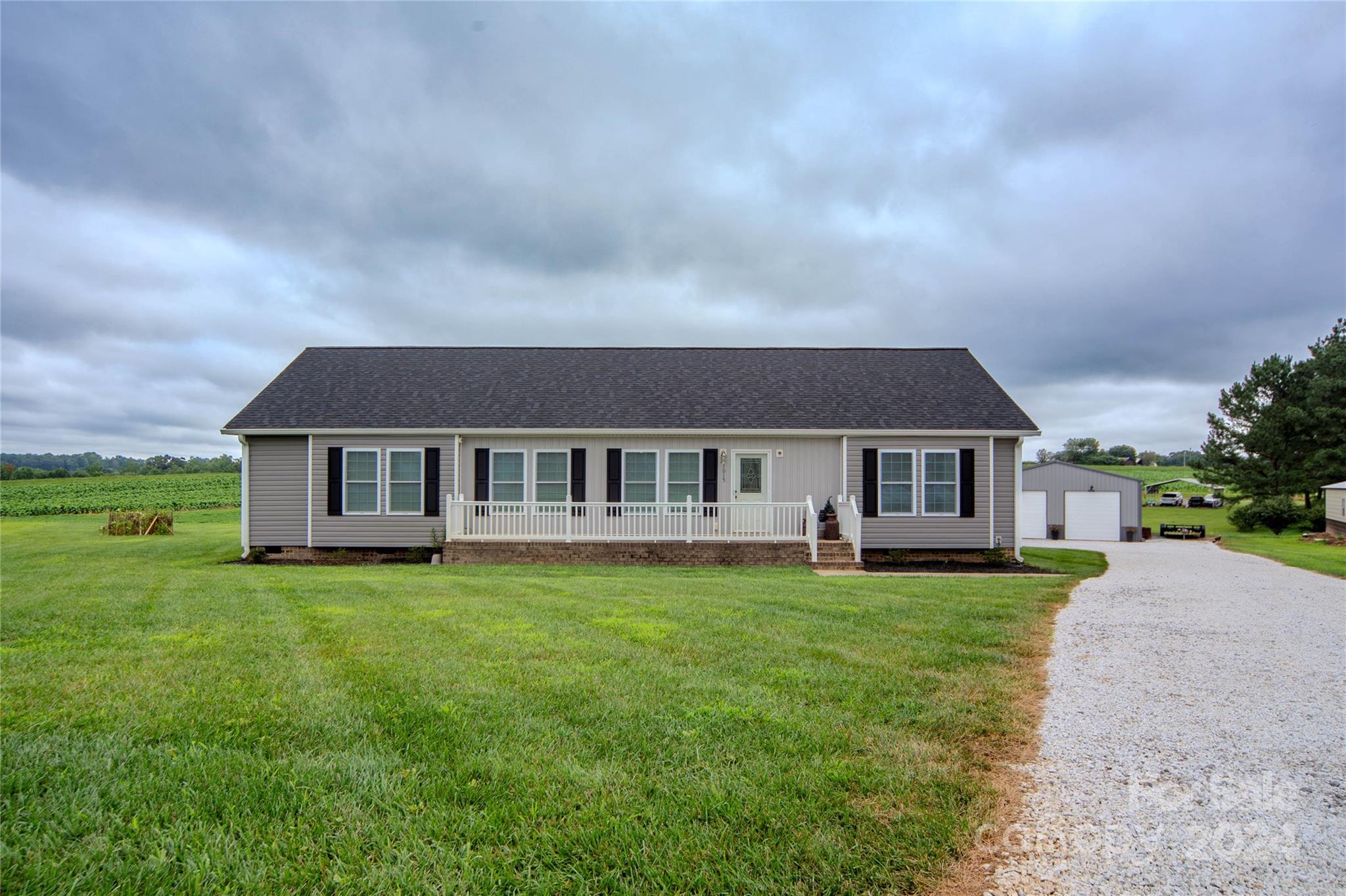 a house that is sitting in the grass with large trees and plants