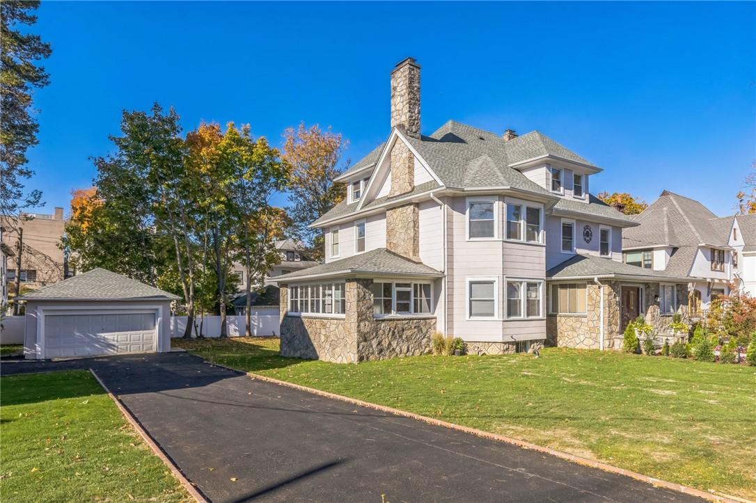 View of front of home featuring a front yard, an outdoor structure, and a garage