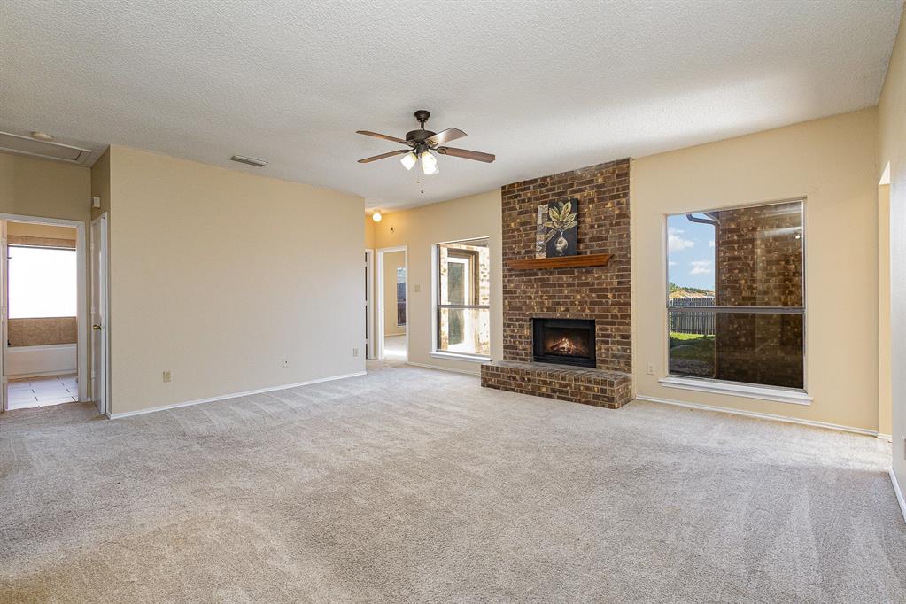 an empty room with windows and fireplace