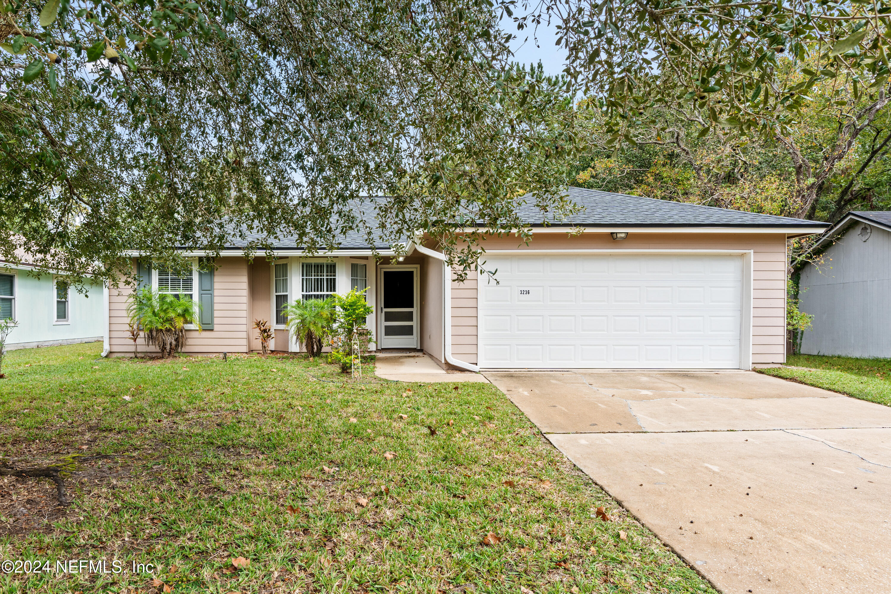 front view of house with a yard and trees all around