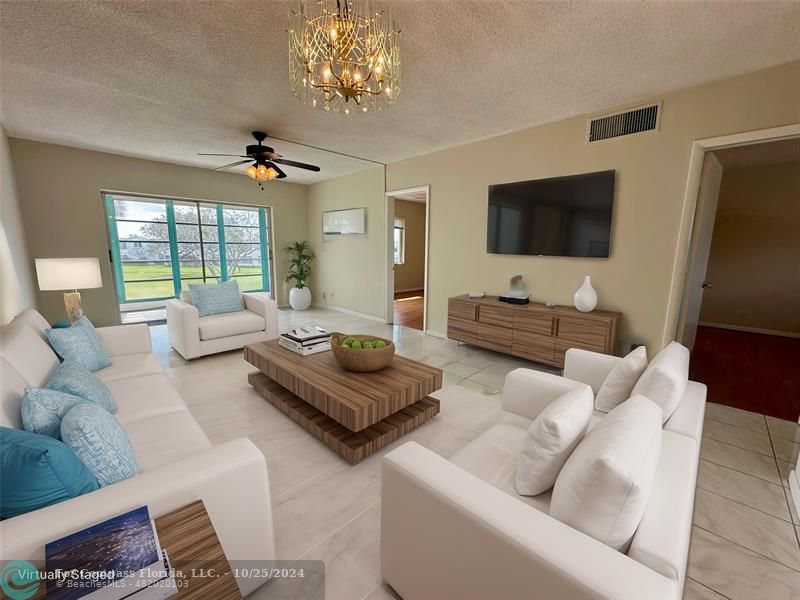 a living room with furniture a flat screen tv and a large window