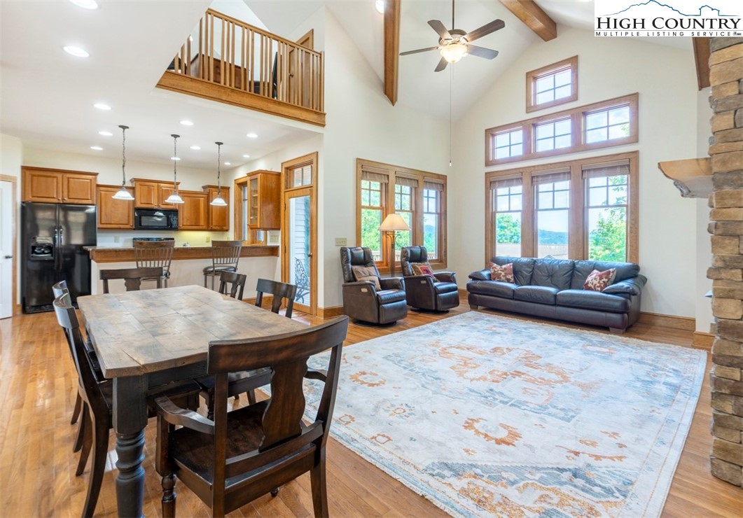 a living room with stainless steel appliances furniture a rug kitchen view and a table