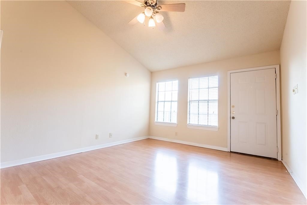 an empty room with windows and chandelier fan