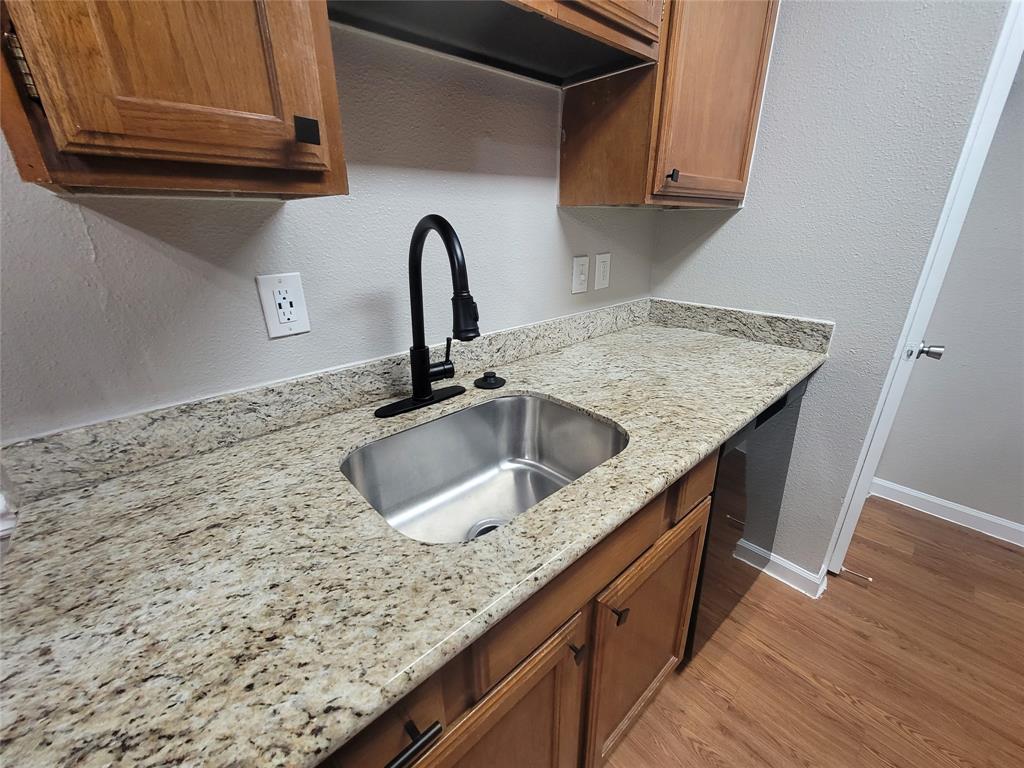 a kitchen with granite countertop a sink and wooden cabinets