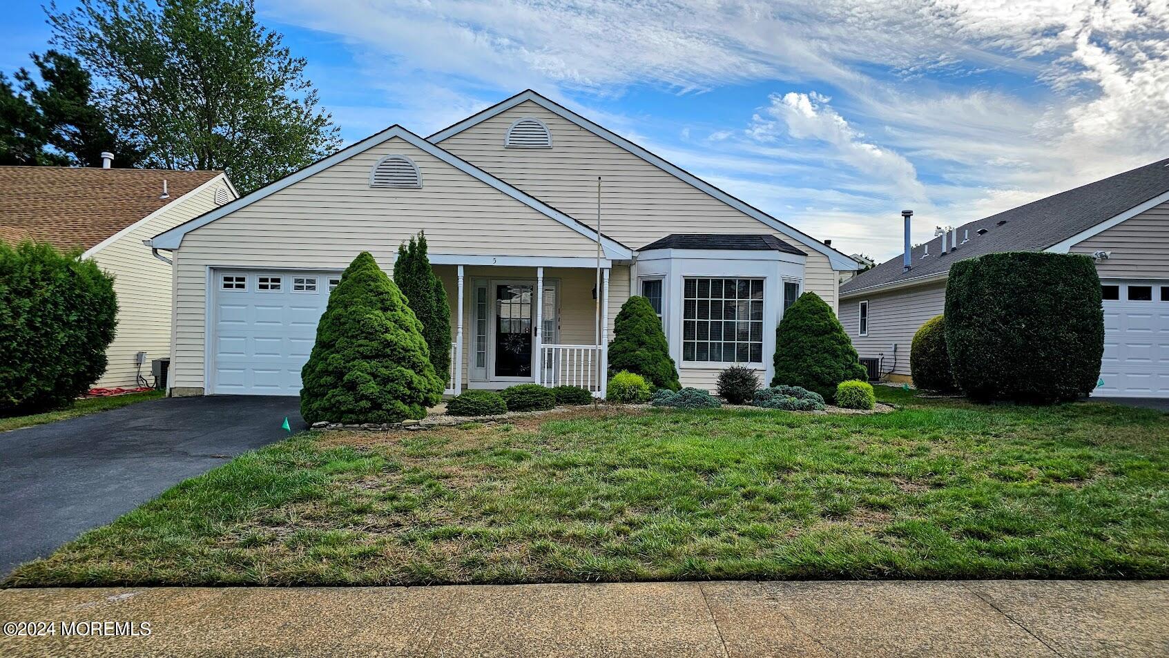 a front view of a house with a yard and potted plants