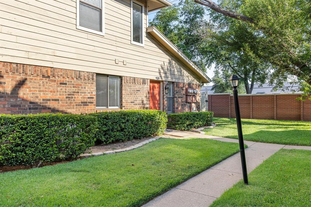 a view of a house with a yard and a large tree