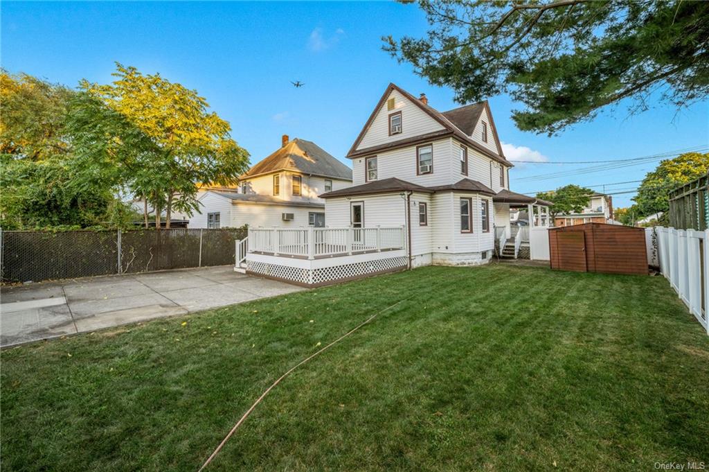 Back of house featuring a storage unit, a patio, a deck, and a yard