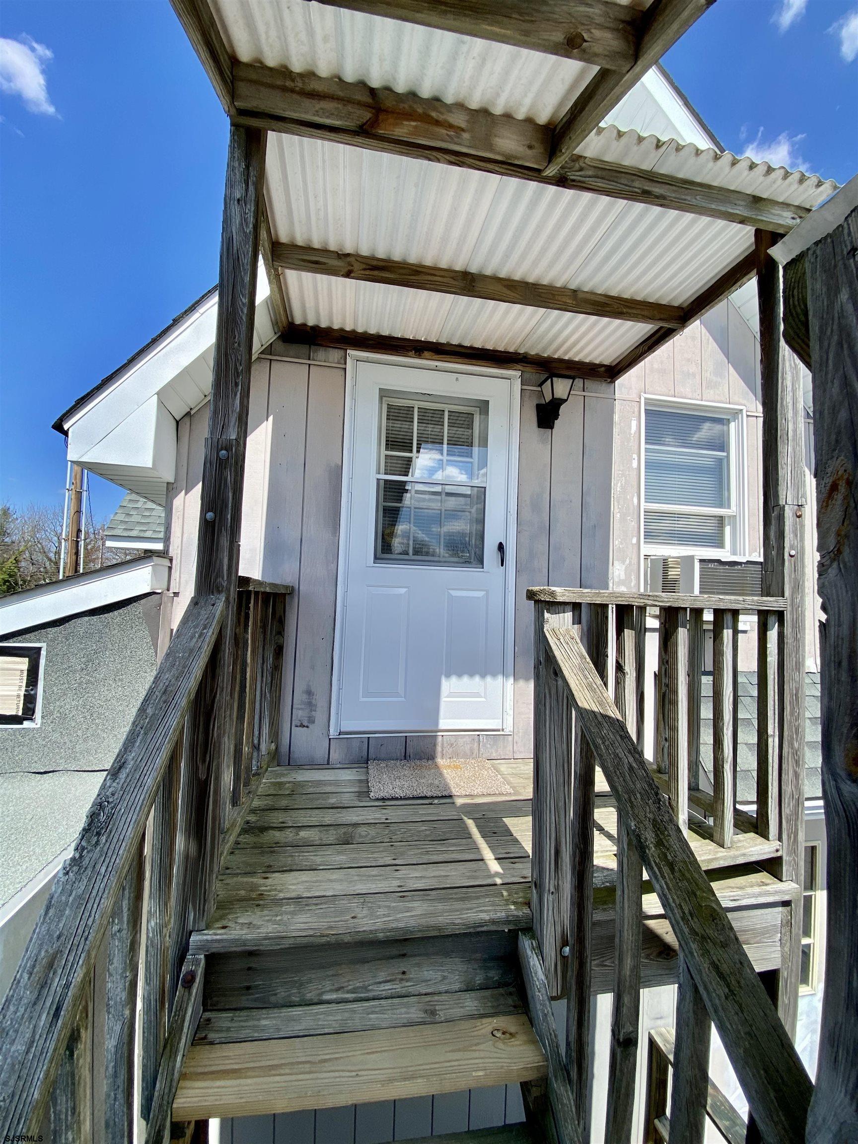 a front view of house along with deck and outdoor seating