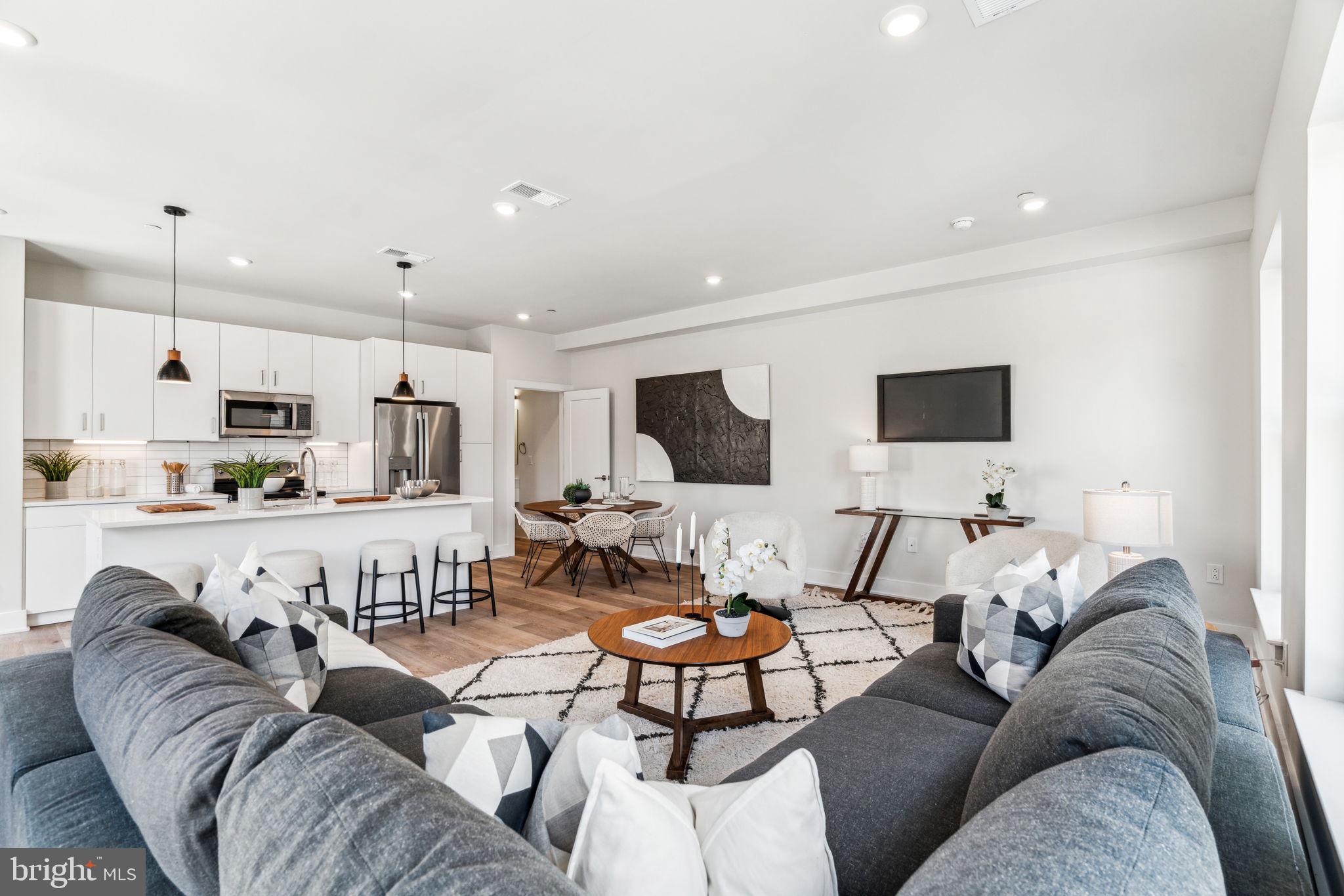 a living room with furniture kitchen view and a flat screen tv