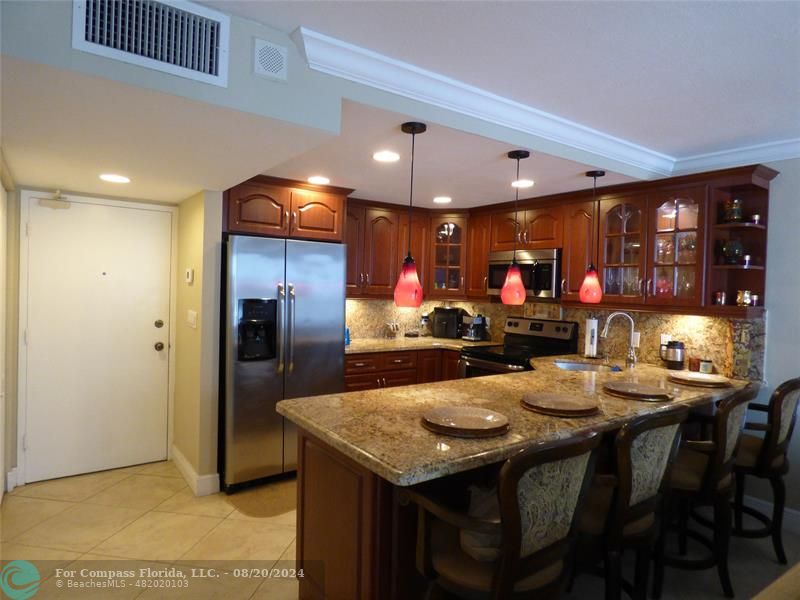 a kitchen with stainless steel appliances kitchen island granite countertop a table chairs and a dining table