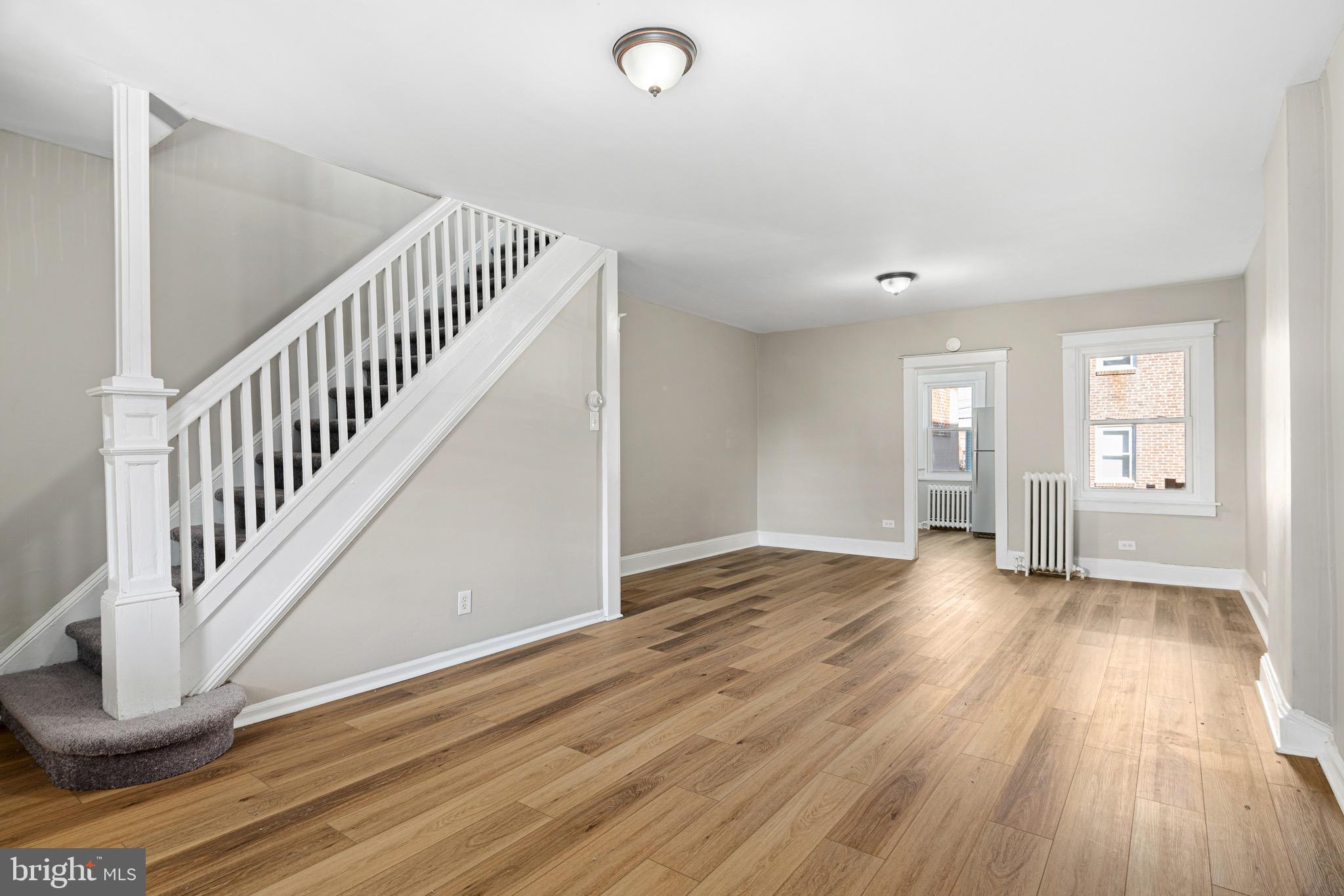 a view of an empty room with wooden floor and windows