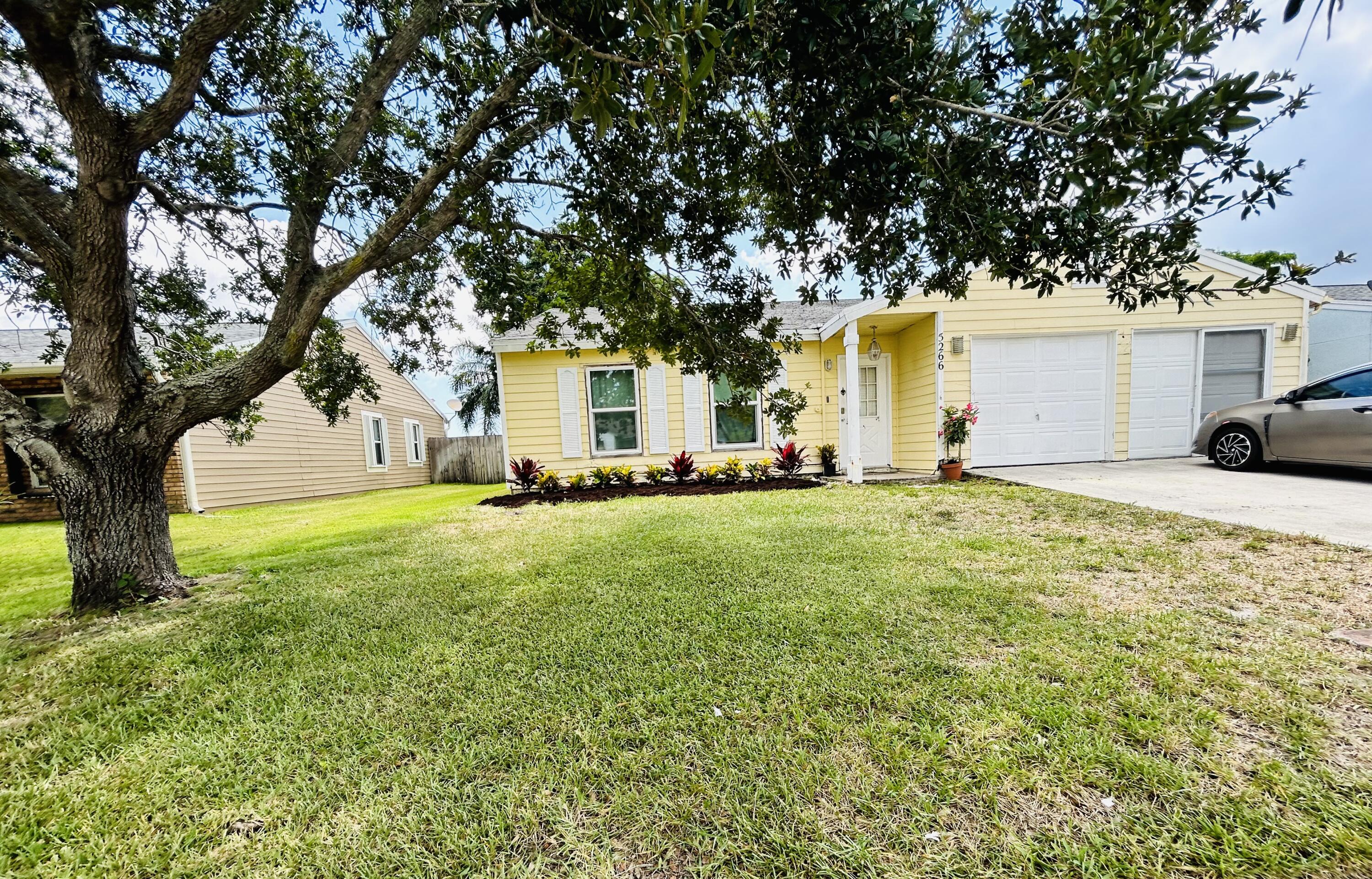 a view of a house with a tree in the grass