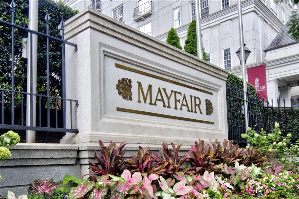 a front view of a building with lots of flowers and trees