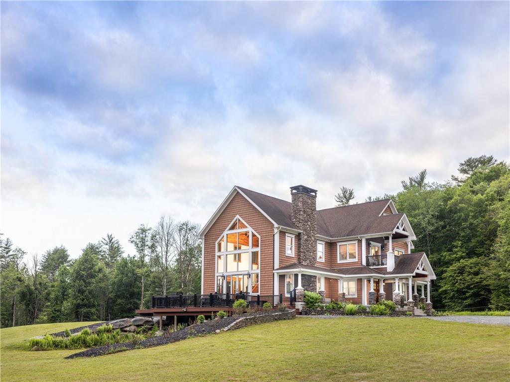 View of front of home with a wooden deck and a front yard