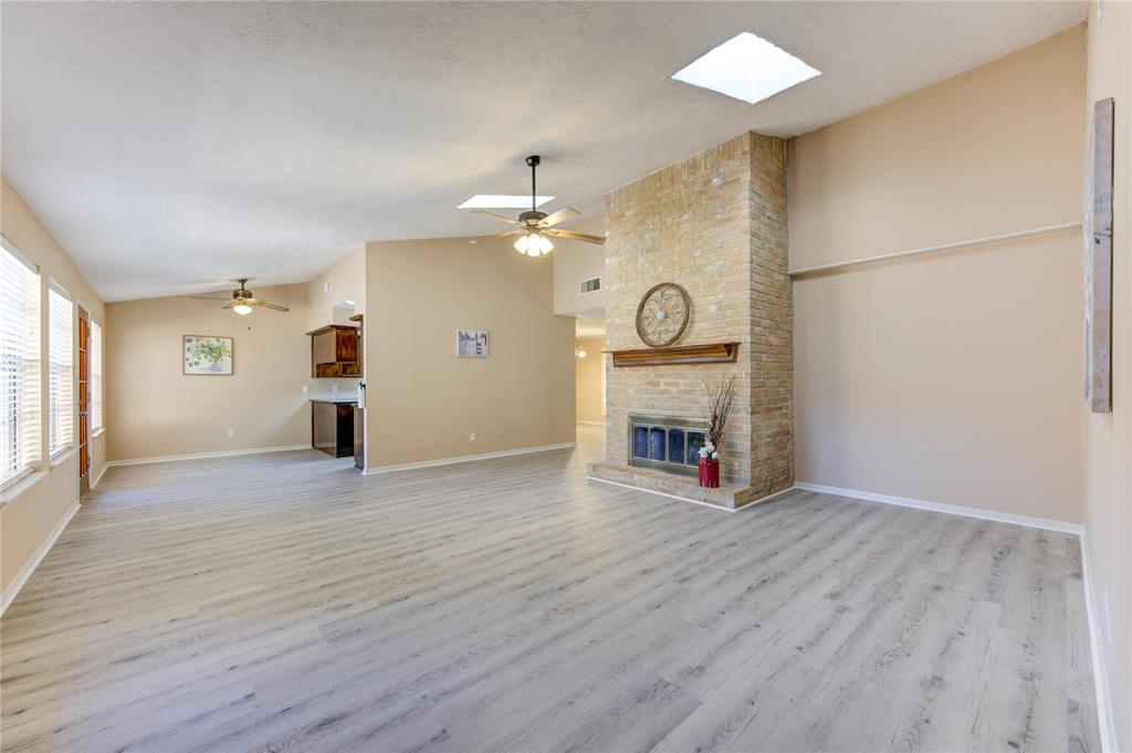 an empty room with windows fireplace and wooden floor