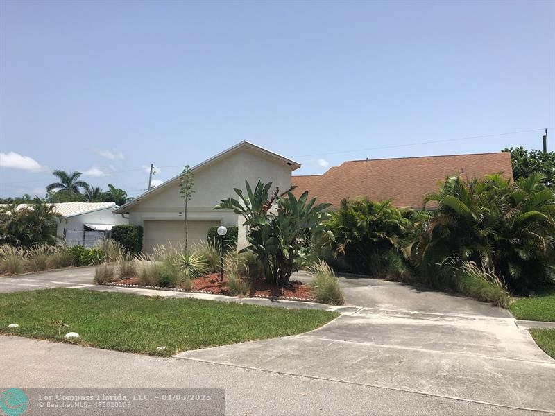 a view of a house with a yard and potted plants