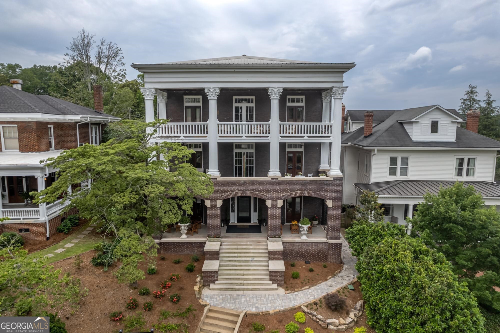 a front view of a house with garden and trees