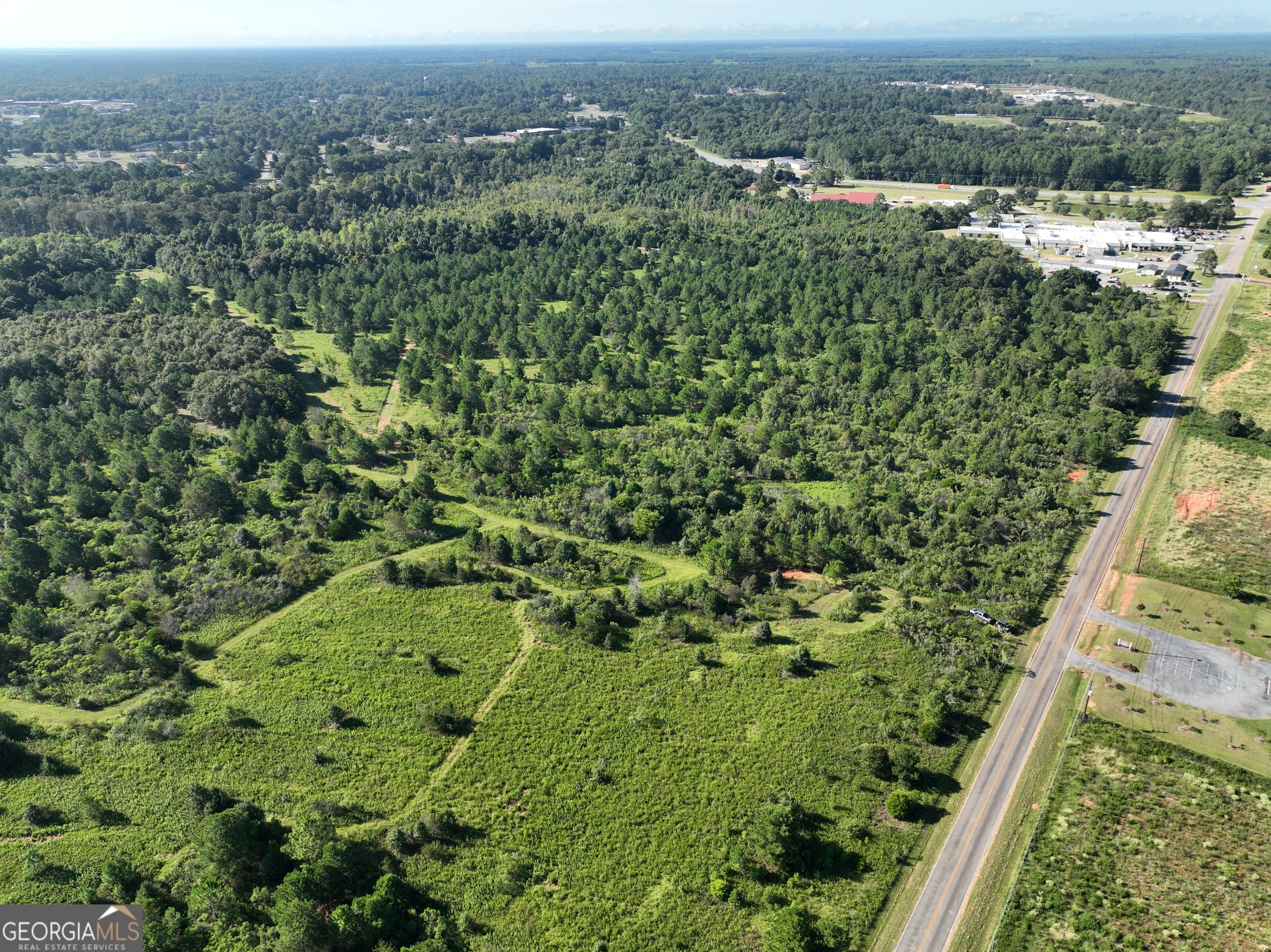 an aerial view of residential houses with outdoor space and trees