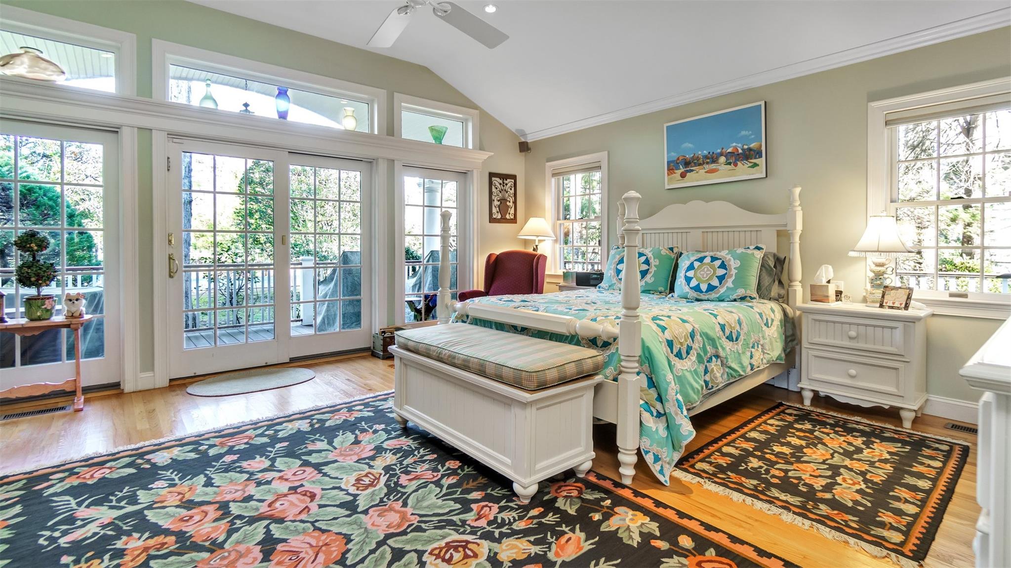 Bedroom with ceiling fan, light hardwood / wood-style floors, vaulted ceiling, and multiple windows