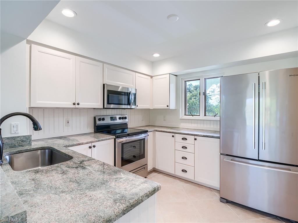 a kitchen with granite countertop white cabinets and stainless steel appliances