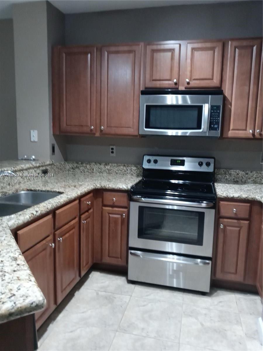 a kitchen with granite countertop a stove top oven microwave and cabinets