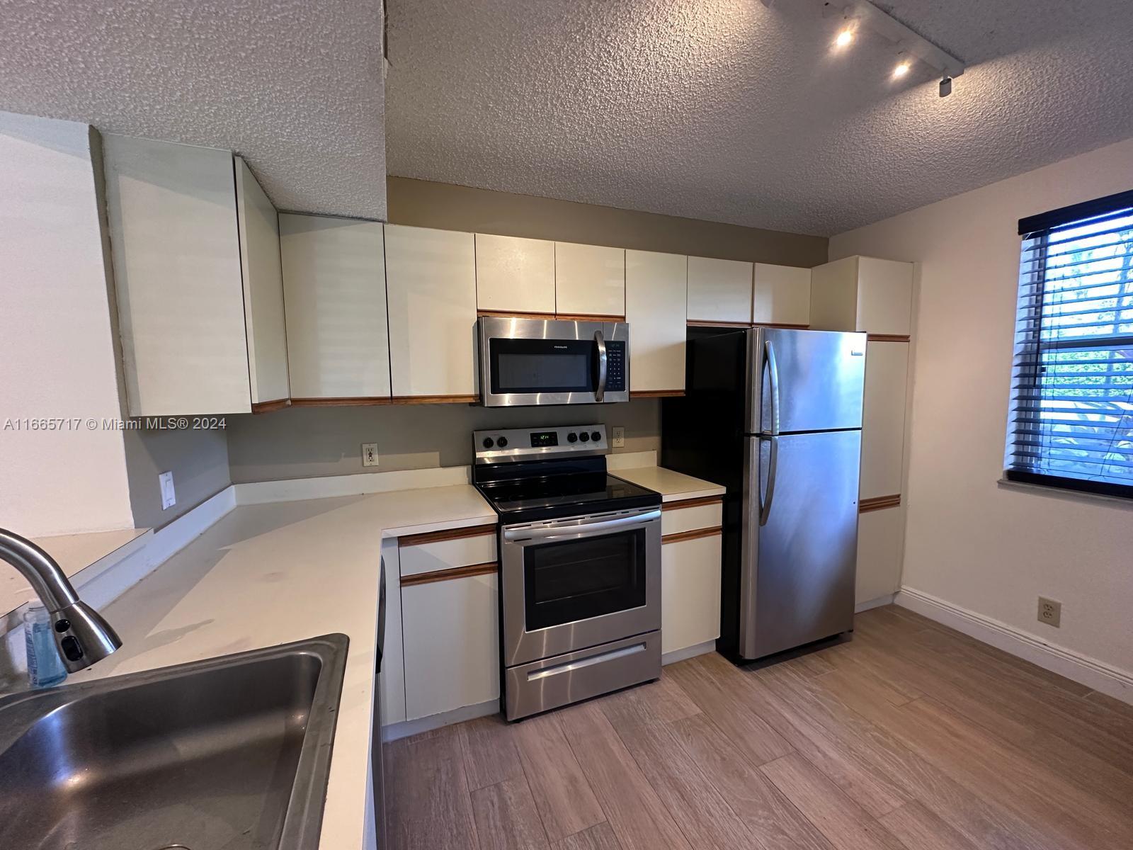 a kitchen with a refrigerator sink and wooden floor