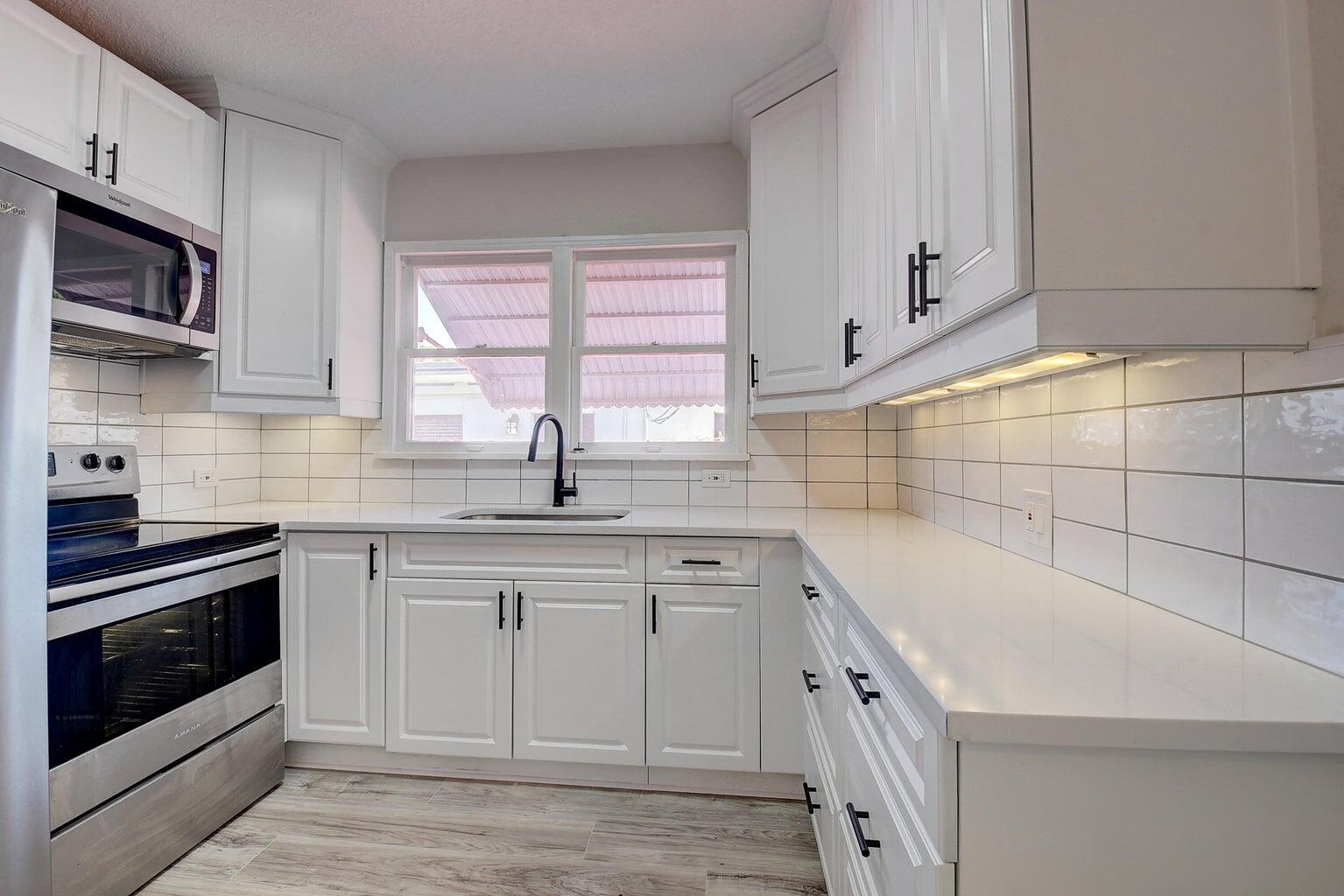 a kitchen with granite countertop white cabinets and white appliances