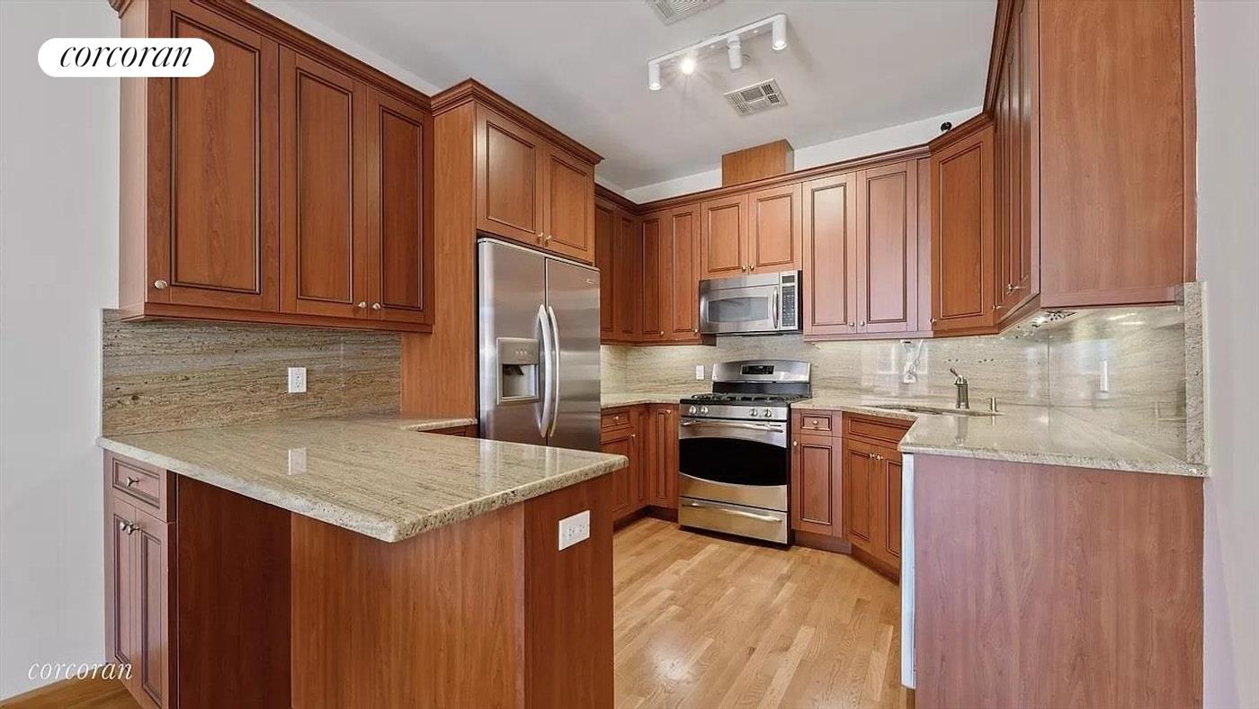 a kitchen with stainless steel appliances granite countertop a refrigerator stove sink and cabinets