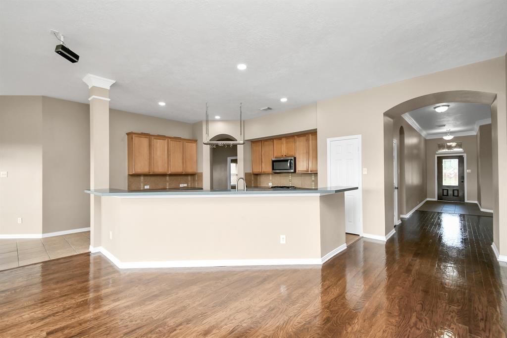 a living room with stainless steel appliances kitchen island granite countertop a refrigerator a sink a stove and white cabinets with wooden floor