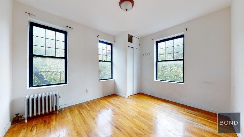 a view of an empty room with a window and wooden floor