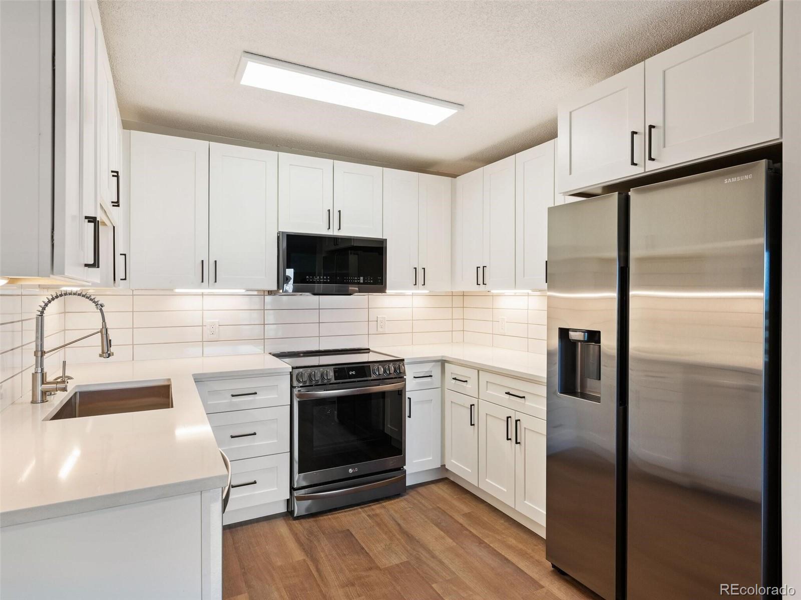 a kitchen with stainless steel appliances granite countertop a refrigerator sink and stove