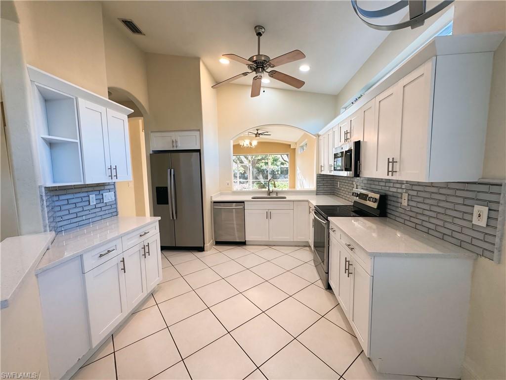 Kitchen with sink, appliances with stainless steel finishes, white cabinetry, and light tile patterned floors