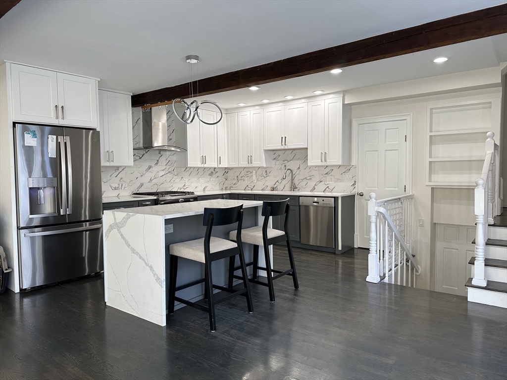 a kitchen with stainless steel appliances granite countertop a table chairs stove and refrigerator