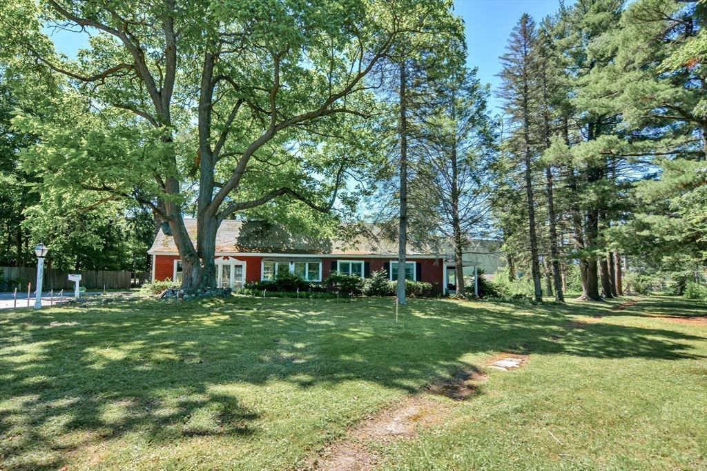 a view of a house with a big yard and large trees