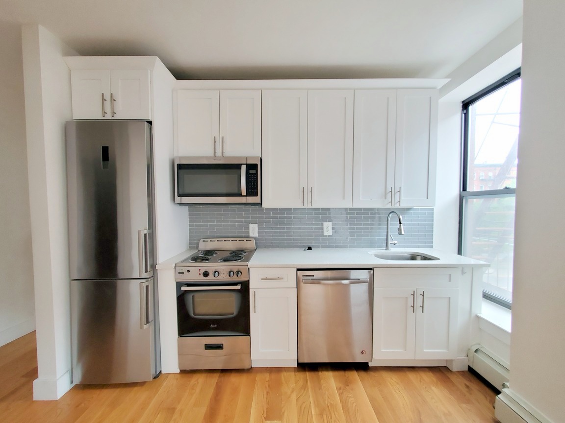 a kitchen with a sink a microwave a refrigerator and cabinets