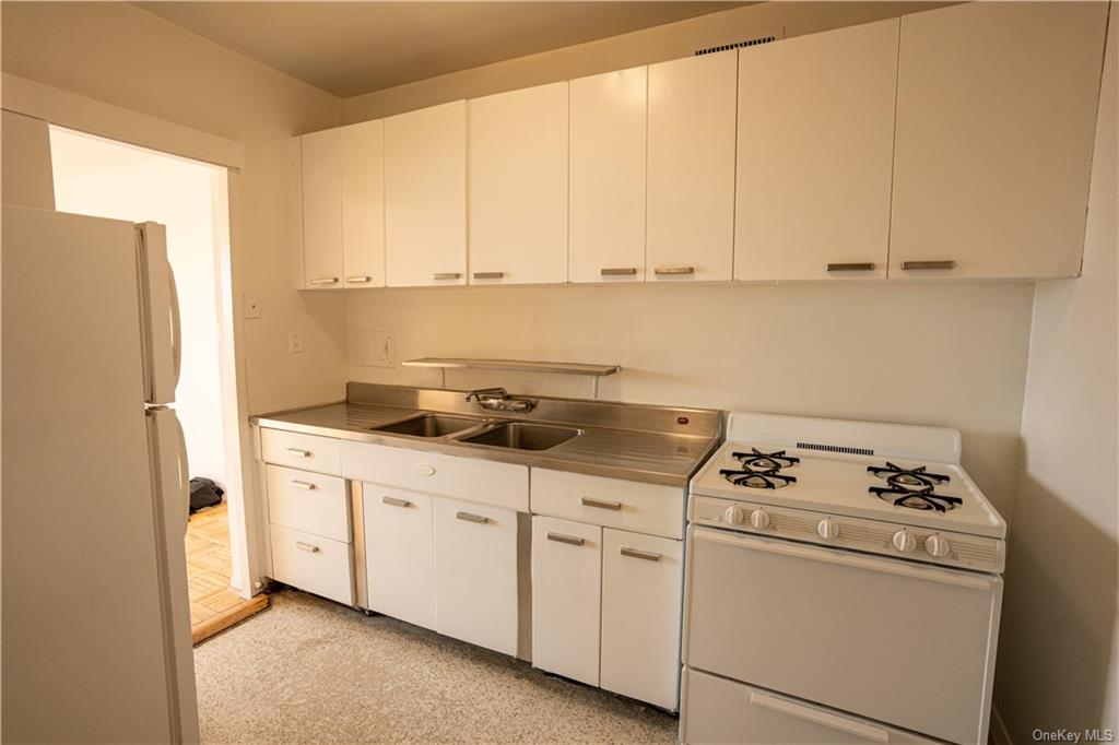 Kitchen with light carpet, white appliances, white cabinetry, and sink