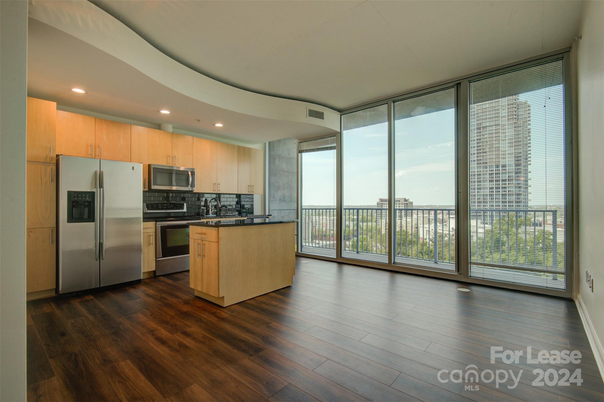 a kitchen with stainless steel appliances wooden floor and large window