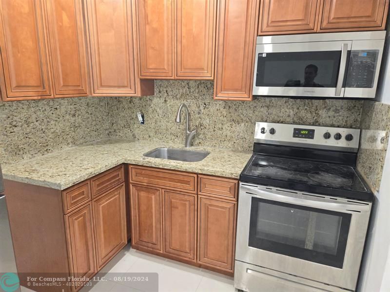 a kitchen with granite countertop cabinets stainless steel appliances and a sink